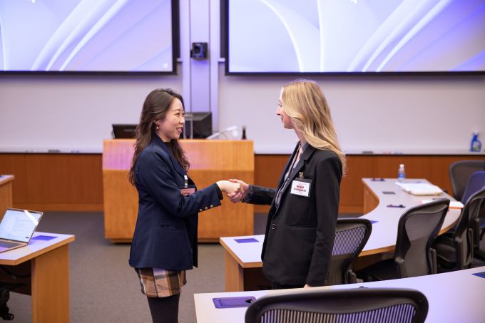 SIA students Yuting Zhang (left) and Brigid Ostrowski shake hands during a negotiation session.